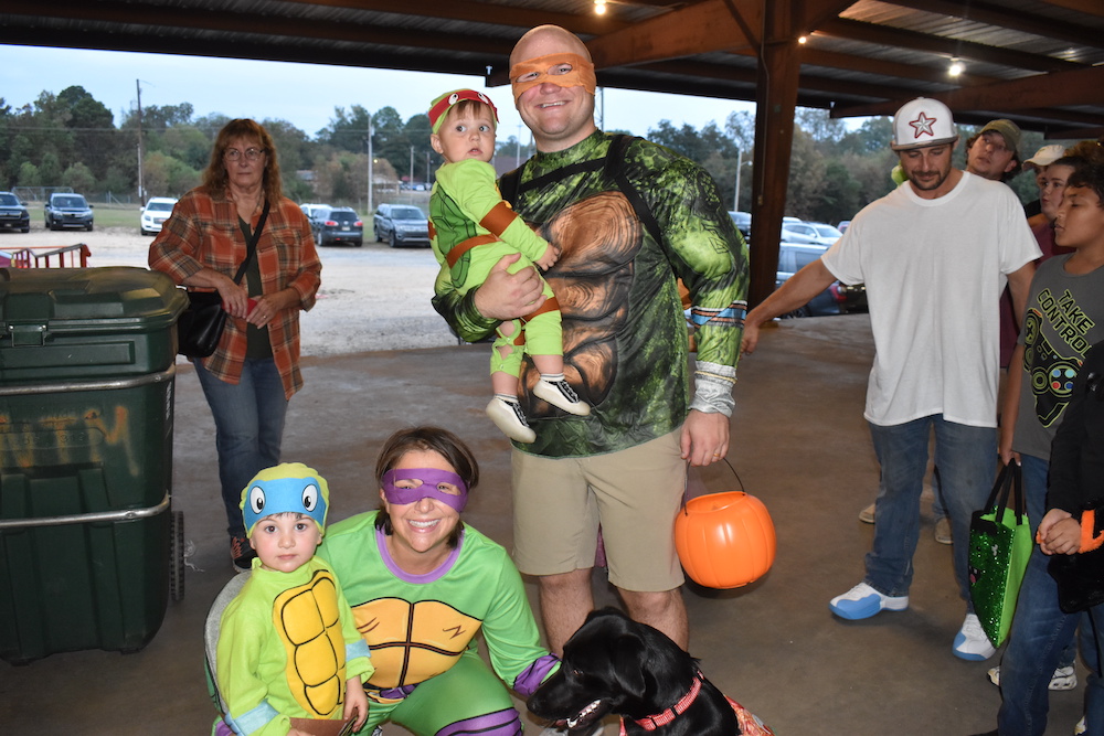 A man and two children dressed as teenage mutant ninja turtles.