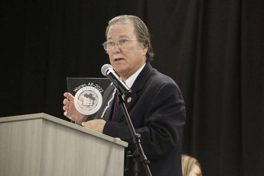A man standing at a podium holding up a plaque.