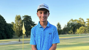 A young man in blue shirt and hat on golf course.