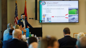 A man standing in front of a projector screen.
