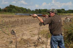 A man is holding a gun in the field