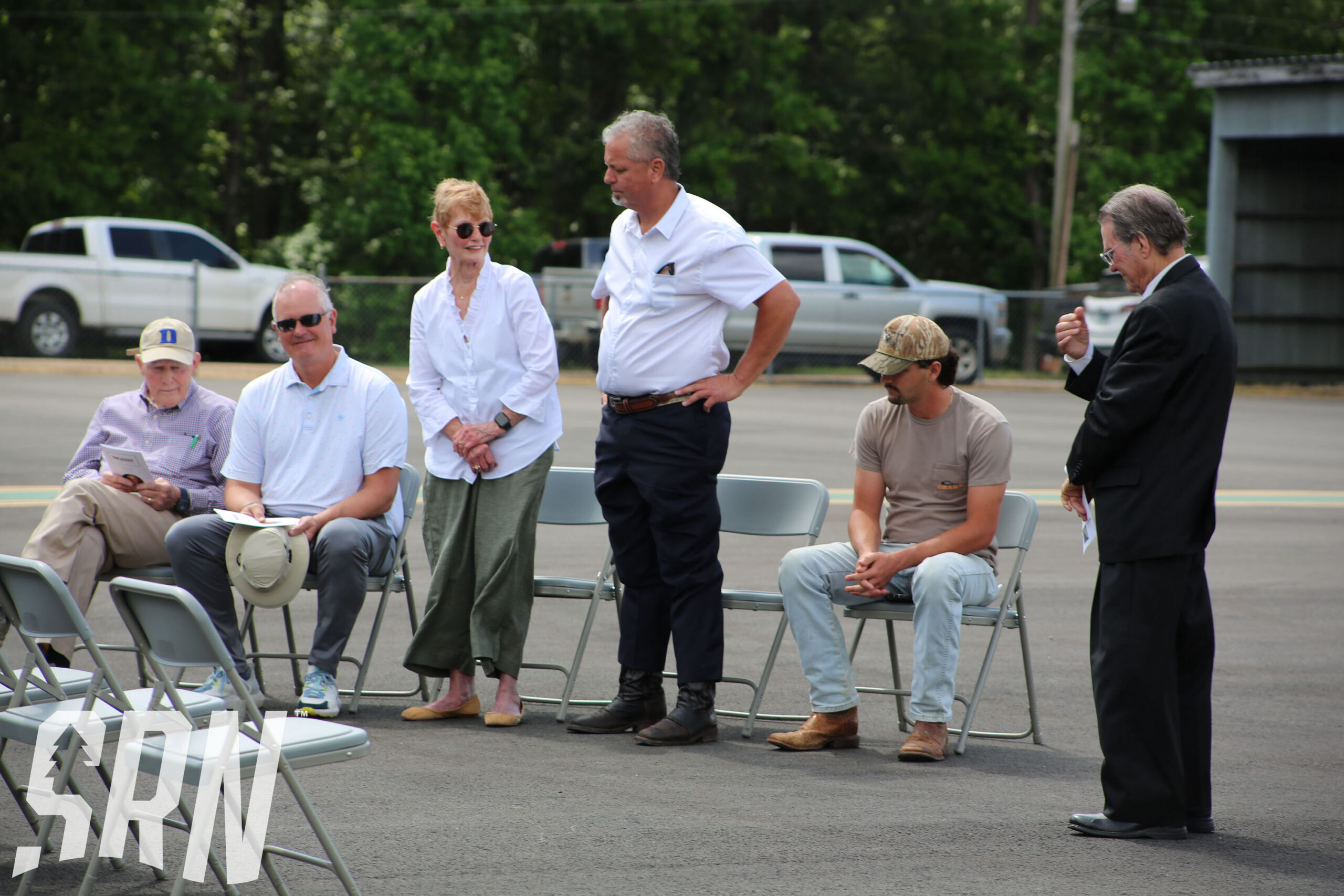 A group of people sitting in chairs on the street.