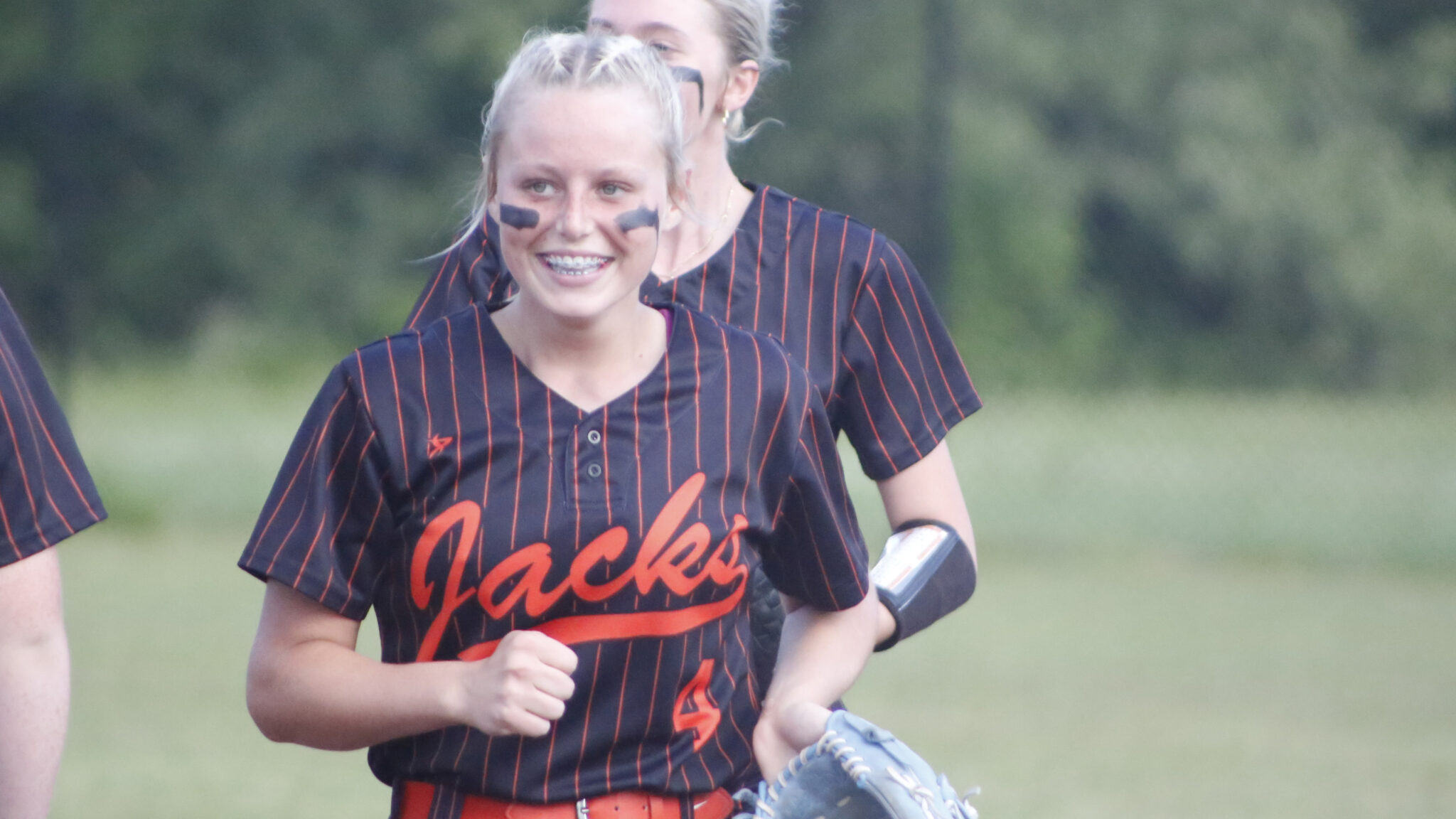 Two girls are playing softball on a field.