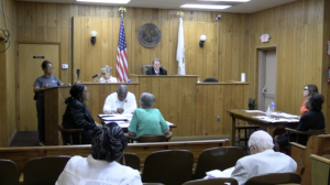 A courtroom with people sitting in front of the judge.