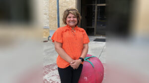 A woman standing next to a pink suitcase.