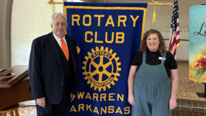 A man and woman standing next to a banner.