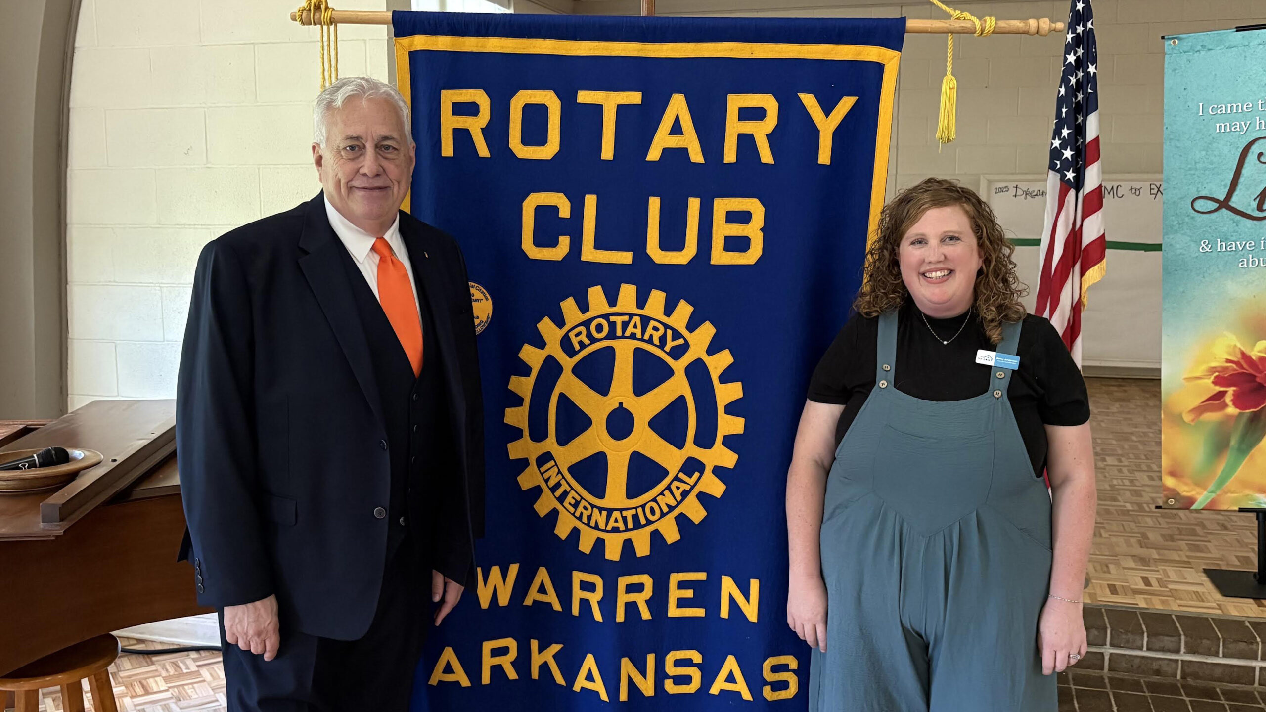 A man and woman standing next to a banner.