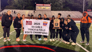 A group of girls holding up a sign and a trophy.